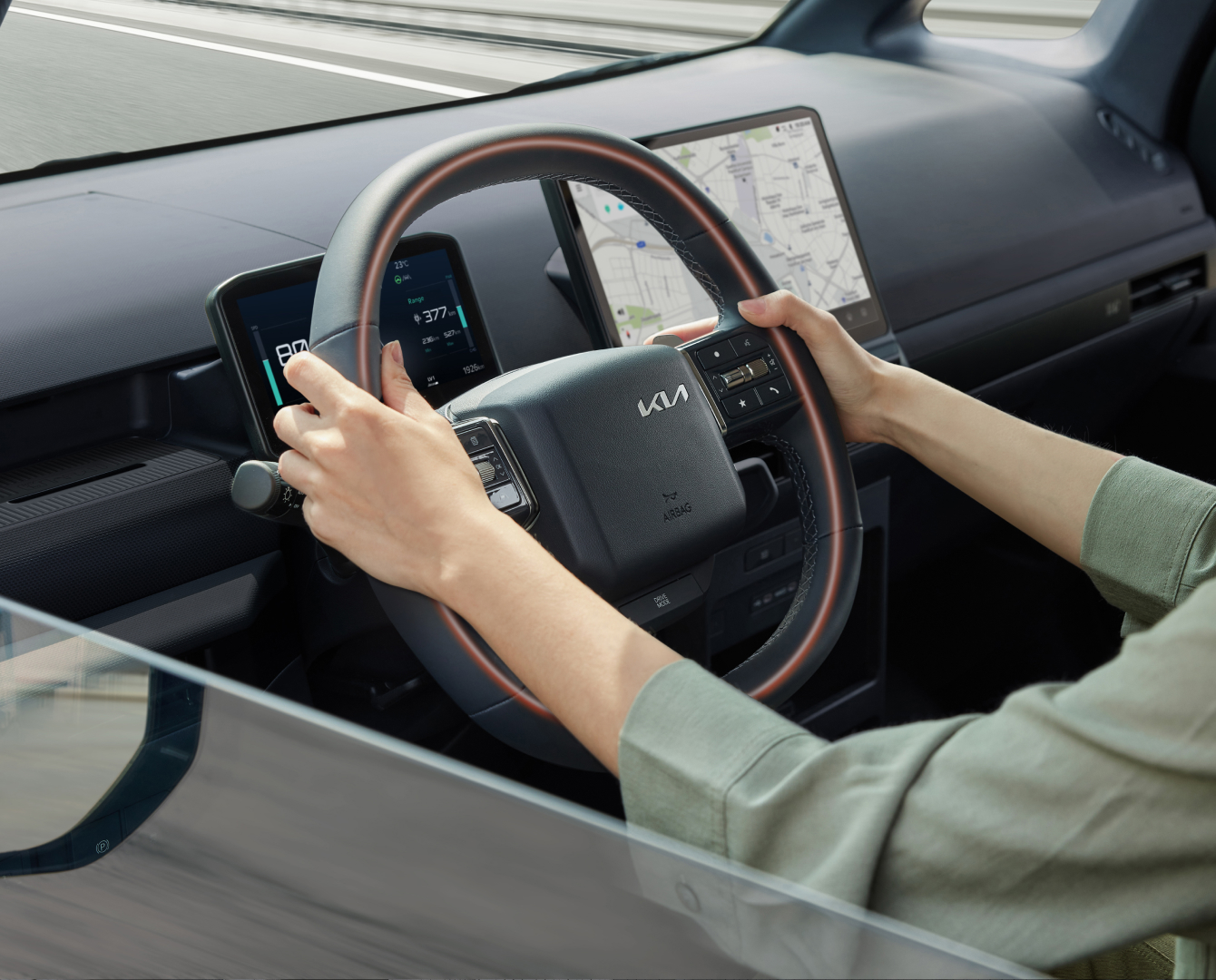 Close-up of the Kia PV5 Cargo steering wheel with driver’s hands
